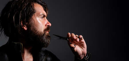 Handsome bearded man with barber tool. scissors. Beard styling and cut. Mens haircut barbershopの写真素材