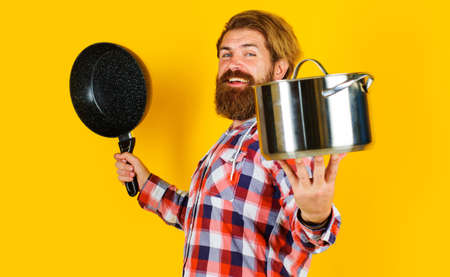 Bearded man with saucepan and frying pan. shopping kitchenware. Cooking utensils for healthy foodの写真素材