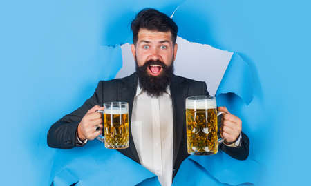 Bearded man with mug of beer looking through paper hole. Lager and dark ale. Drinks, alcohol, barの写真素材