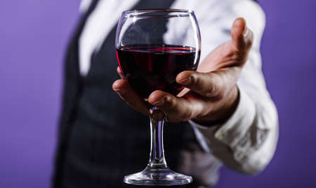 Man hand with glass of red wine. Tasting alcohol. wine tour. Male sommelier with wineglass. close upの写真素材