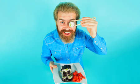 Man eating sushi. Handsome male with maki rolls on chopsticks. delivery service. Japanese foodの写真素材