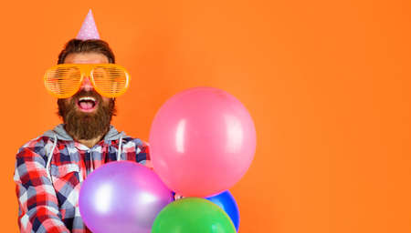 Bearded guy in funny glasses and cone hat with balloons. Man on party. Happy birthday celebratingの写真素材