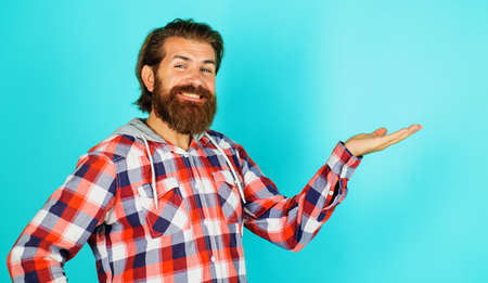Smiling bearded man shows something on palm hand with copy space for product. advertising. Discountの写真素材