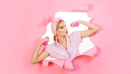 fitness training. Sporty girl with dumbbells look through paper. Woman athlete with sports equipmentの写真素材