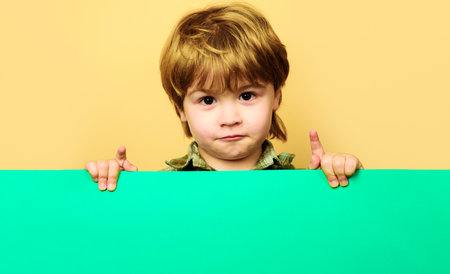 Child boy with empty billboard. Little kid with blank sign board. Advertising of children's goodsの写真素材