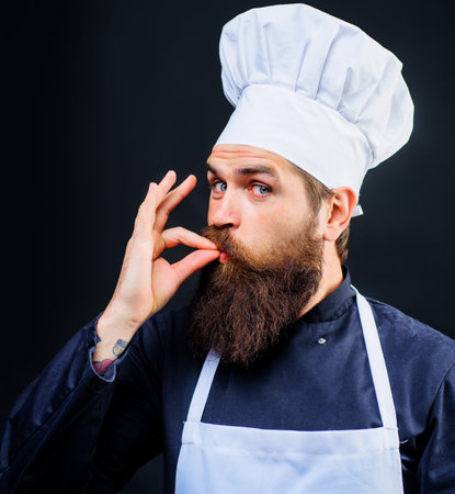 Male chef or baker in white hat and apron gesturing excellent. Cook with taste approval gestureの写真素材