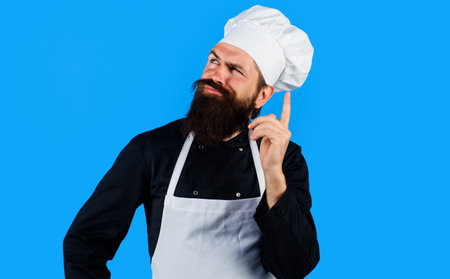 Professional chef in uniform composing new menu. Bearded cook in hat and apron thinks what to cookの写真素材