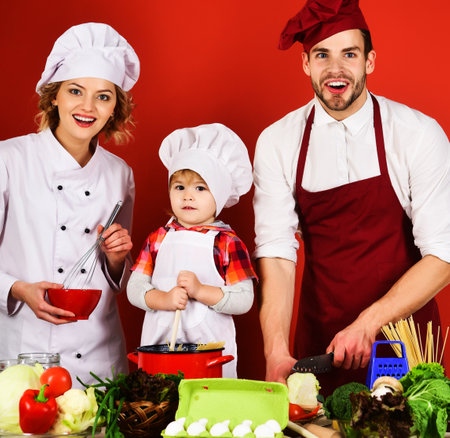 Happy family preparing healthy food in kitchen at home. Mother and father teach little son cookingの写真素材