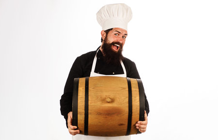 Brewer in brewery with wood barrel. Oktoberfest. Bearded man in chef hat and apron with cask wineの写真素材