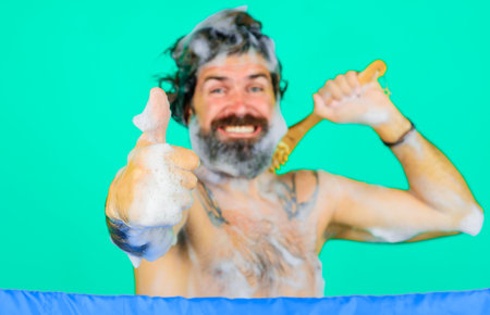 Man with bath brush washing body shows thumb up. bearded guy taking shower showing sign okの写真素材
