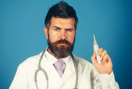 Medicine, vaccination and healthcare concept - male doctor or scientist in uniform with syringeの写真素材