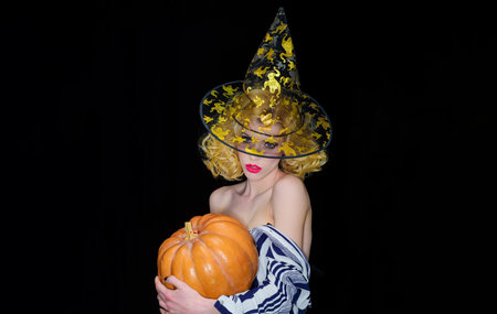 Happy Halloween. Sensual girl with pumpkin. Trick or treat. sexy girl in witch hatの写真素材
