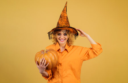 Halloween party girl with pumpkin. Smiling woman in witch hat with jack-o-lanternの写真素材