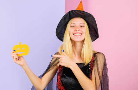 Halloween holiday. Smiling woman with paper pumpkin. Happy girl in witch hat. October 31の写真素材