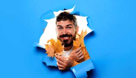 Smiling man with golden maple leaves. Happy bearded man in warm clothes. Autumn fashion for menの写真素材