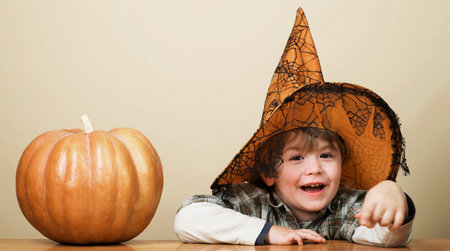 Child in witch hat with halloween pumpkin. Smiling little boy preparation for Halloween holidayの写真素材