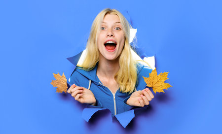 Autumn mood. Smiling girl with maple leaves looking through paper hole. autumn sale. Discountの写真素材