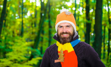 Smiling bearded man in warm clothes in the park on a sunny day. fall season. male autumn fashionの写真素材