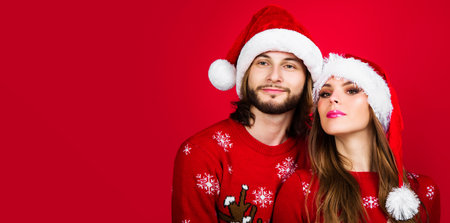 Young couple in Christmas sweaters and Santa hats. Happy New Year celebration. Merry holidaysの写真素材