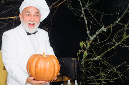 Harvest pumpkin. Bearded cook in chef hat with pumpkin. farm market. autumn vegetables. diet foodの写真素材