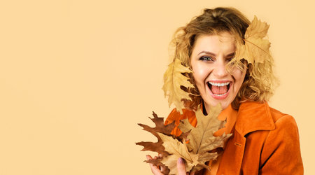 Happy woman in orange jacket with yellow leaves. fashion autumn girl. fresh skin. healthy smileの写真素材