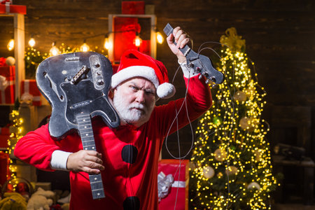 Merry Christmas. New Year party. Bearded Santa Claus rock musician with broken electric guitarの写真素材