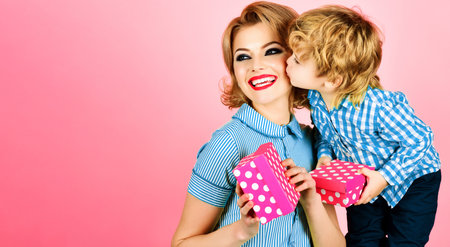 Little son kissing happy mother and gives gifts box congratulating on mothers day. Family holidaysの写真素材