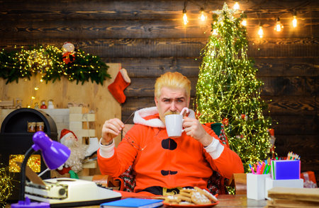 Santa Claus with mug of milk and cookie sitting at table. Christmas backgroundの写真素材