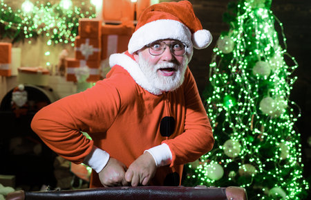 Santa Claus with vintage leather suitcase going on trip. New Year's travel. Concept of vacationの写真素材