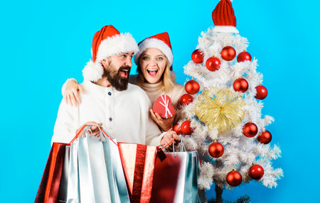 Christmas or New year shopping. Happy couple with shopper bags near Christmas tree. Sale, discountの写真素材