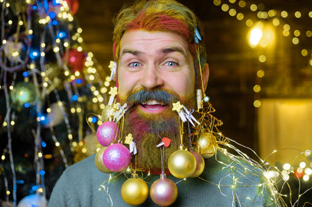 Happy bearded man with decorated beard. New year party. Christmas decorations. Winter holidaysの写真素材