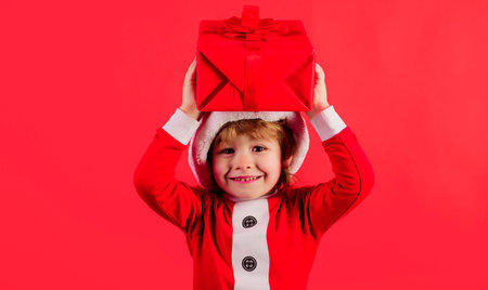 Little Santa Claus gifting gift. Christmas child with present box. Preparing for New Year holidaysの写真素材