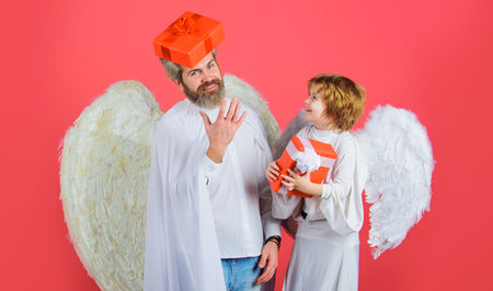 Valentines day. Father in angel costume and little son in angelic wings with present. Cute angels