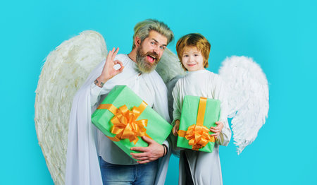 Little angel child with gift and bearded man in angelic wings shows sign ok. Valentine's day shoppingの写真素材