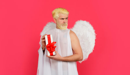 Happy Valentines Day. Cupid with present box. Serious man in angel costume with gift. February 14の写真素材
