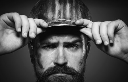 Builder man. Closeup portrait of serious builder in protective hard hat. Building industry. Male...