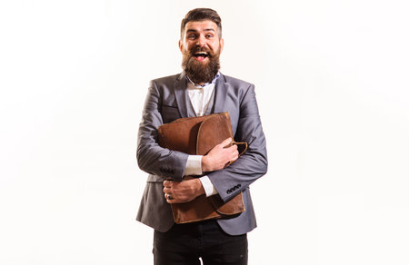 Successful businessman in suit with briefcase. Office worker, business man. Handsome male with stylish hairstyle holds men's brown briefcase. Smiling bearded man with leather briefcase for documentsの写真素材