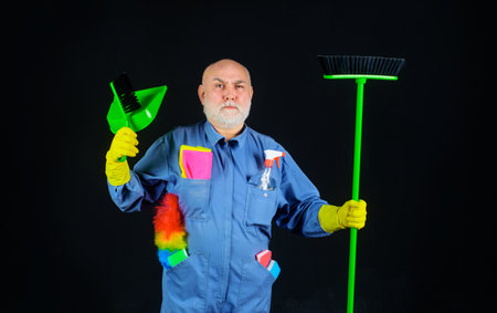 Cleaning day. Bearded man in uniform with broom, dustpan and brush for carpet. Cleaning agency....