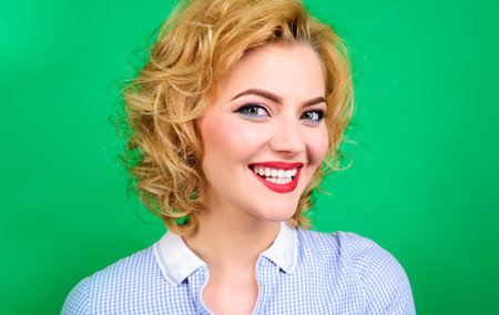 Beautiful young woman with healthy clean skin, perfect bright makeup and red lipstick on lips. Portrait of smiling pinup woman. Retro style. Cosmetology. Skincare and haircare cosmetics. Beauty salonの写真素材