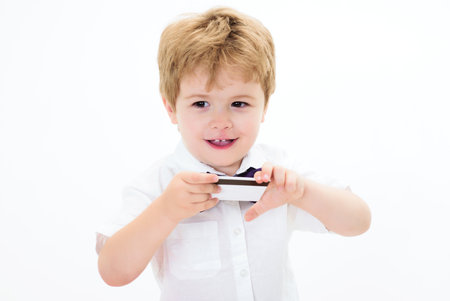 Credit card. Smiling child with credit or debit card. Little boy showing mockup template bank card with magnetic stripe. Payment transaction, e-money, financial success. Banking service advertisingの写真素材