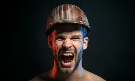 Closeup portrait of angry architect, foreman or builder in hard hat. Handsome screaming engineer or construction worker in safety helmet. Hard work. Shouting builder man in hardhat. Building industry.の写真素材