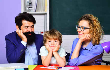 Private lesson. Pupil of primary school having lesson with private tutors. Elementary school teachers and cute schoolboy sitting at table in classroom. Male and female teacher with schoolboy at desk.の写真素材