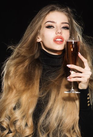 Woman drinking champagne. Beautiful sexy woman with natural makeup raising glass of champagne. Wine tasting. Sensual girl with long hair holding glass of champagne. Christmas and New Year celebrationの写真素材