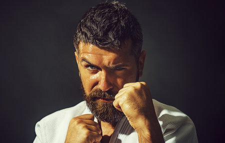 Karate man. Closeup portrait of karate man with clenched fists. Professional karate fighter in kimono preparing for competition. Strong muscular fitness male model in kimono ready for karate trainingの写真素材