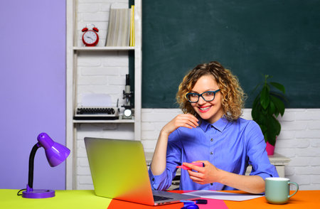 Exam in college. Student girl working with laptop and taking notes. Online lesson. Smiling female...