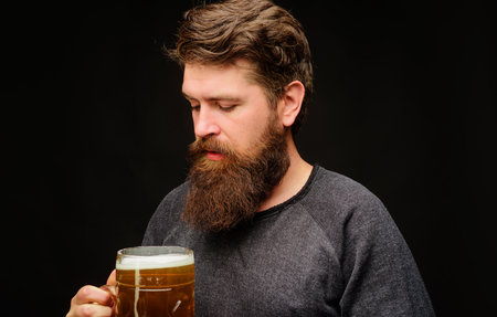 Bearded man with large mug of draft beer. Germany tradition. Stylish man with glass of cold beer. Handsome man drinking beer in pub or bar. Alcohol and leisure. Craft beer at restaurant.の写真素材