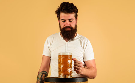 Oktoberfest. Serious brewer with large mug of craft beer on wooden barrel. Draft beer for...