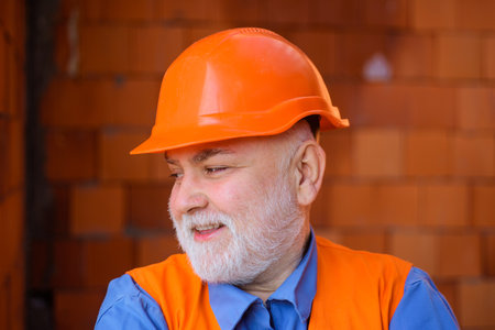 Portrait of smiling architect or engineer in work clothes at workplace. Male builder in protective...