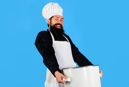 Smiling male chef carrying heavy big pot or saucepan. Cooking and culinary. Bearded cook in uniform...