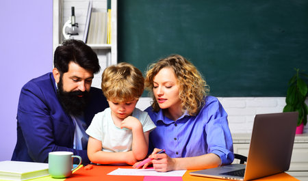 Father, mother and son doing homework together. Education in primary school. Child boy having lesson with private tutors in classroom. Back to school. Couple teachers helping child doing homeworkの写真素材
